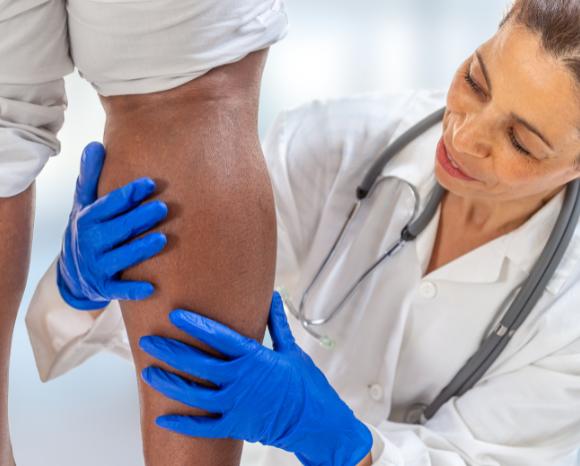 doctor wearing gloves examining patient leg