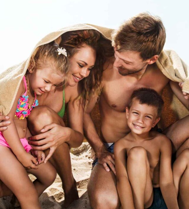 family at the beach with a towel to cover them