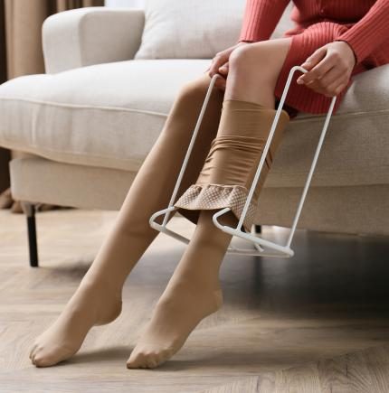 woman using assistive device to put on compression stockings
